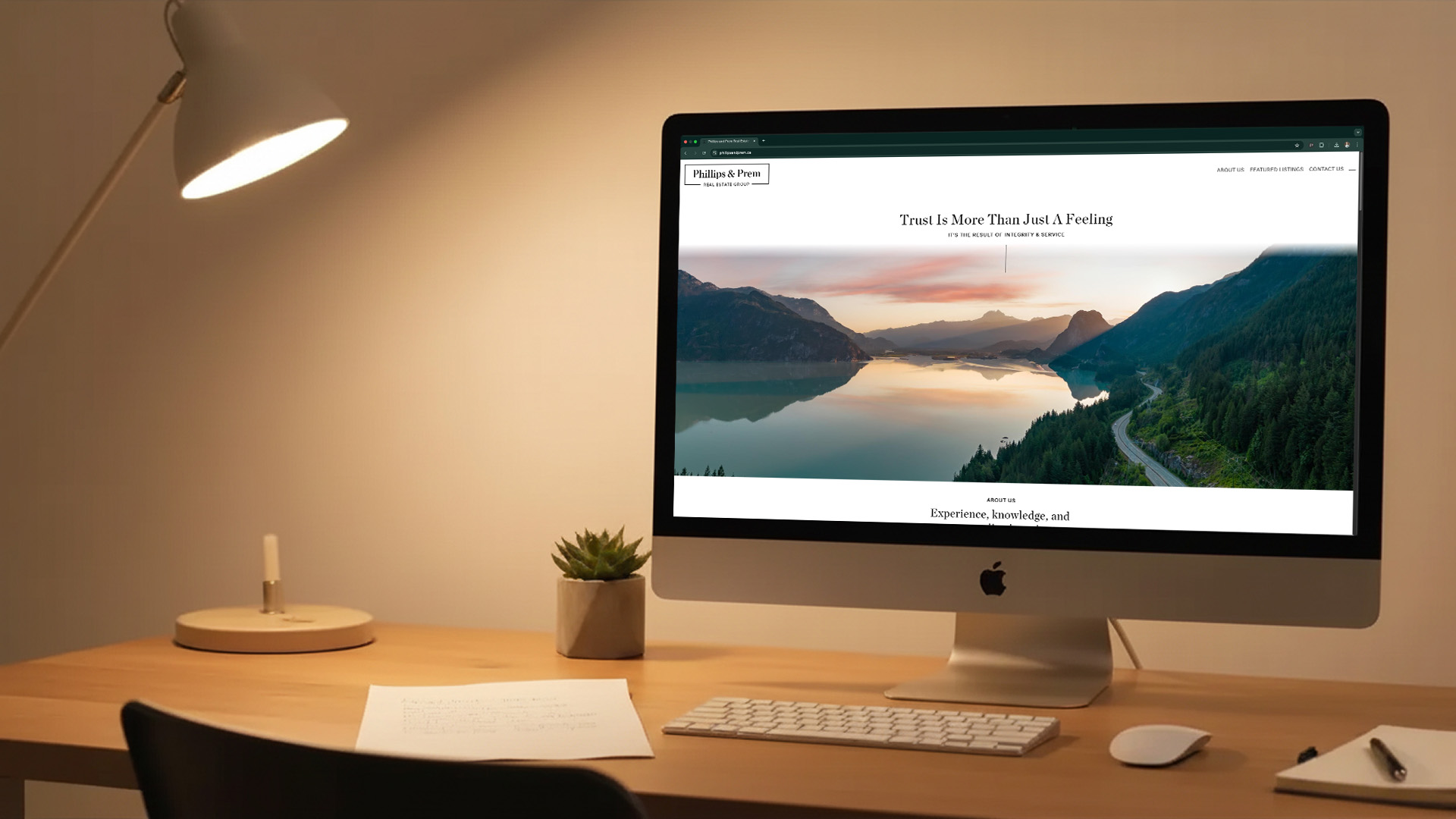 Phillips & Prem Homepage featured on a gold iMac sitting on a clean desk in golden lamplight.